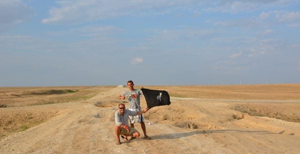 Showing our Drama of Llama team flag on the road we dared not ride.bad road in Kazakhstan